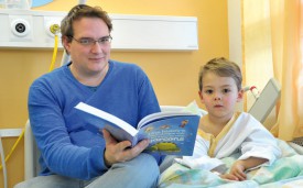 Philippe Oguey et son fils Liam lisent et jouent en attendant l’opération. © Michel Duperrex