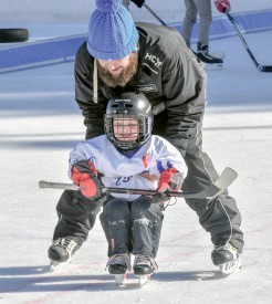 Romain, 3 ans, soutenu par le «Viking» du HC Vallorbe, l’entraîneur Gérard Sulzener. ©Pierre Blanchard